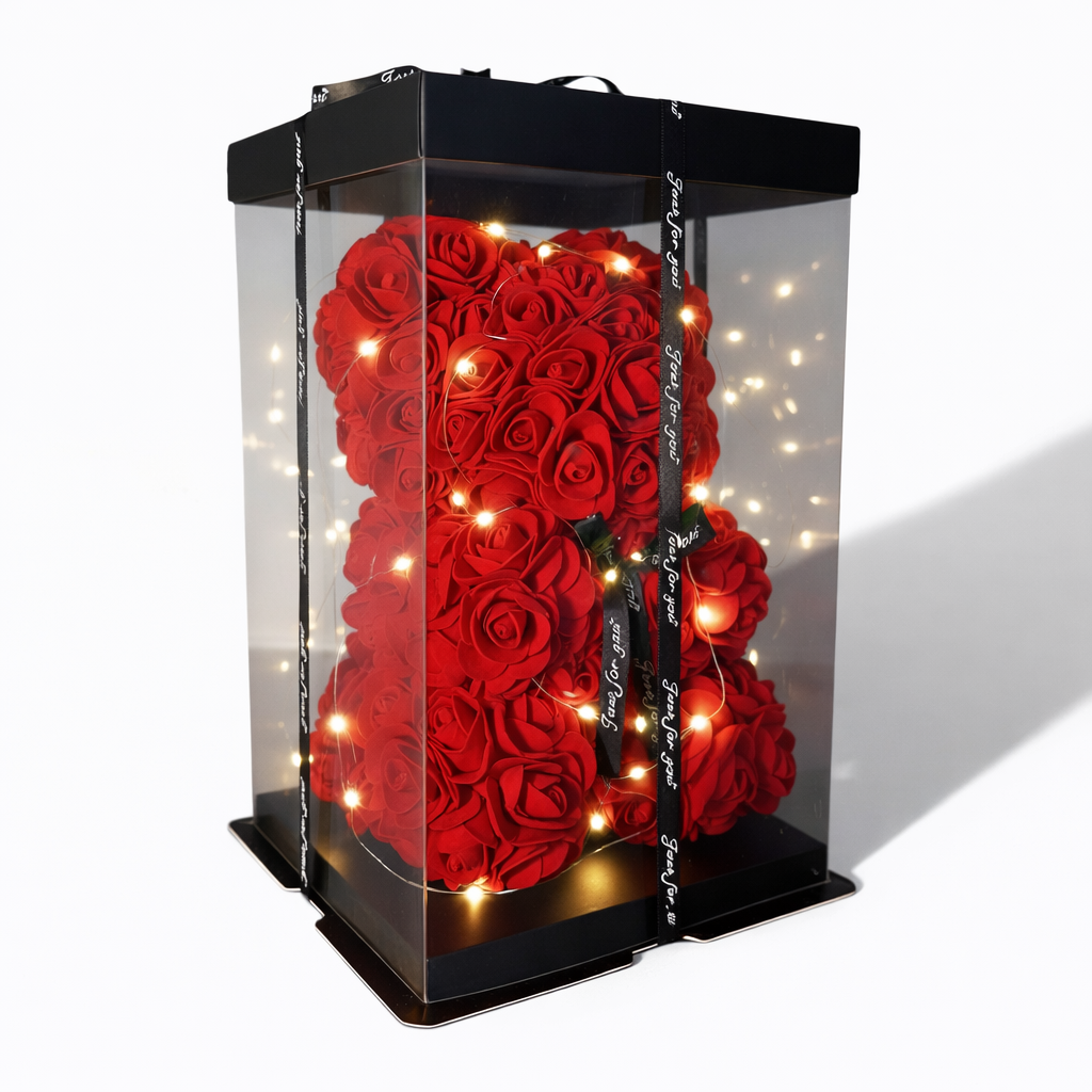 Czerwony miś wykonany z piankowych róż, ozdobiony światełkami LED, zamknięty w przezroczystym ozdobnym pudełku z czarną wstążką.